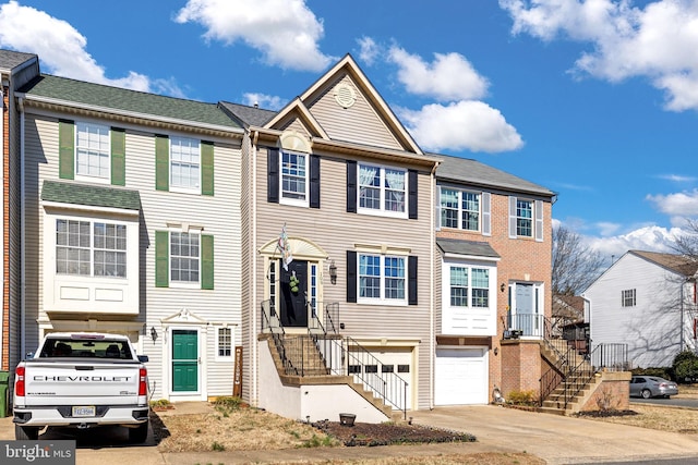 townhome / multi-family property with driveway, stairs, a garage, and brick siding