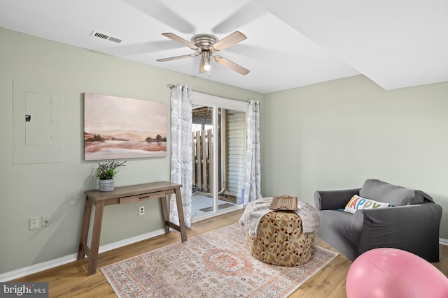 sitting room with visible vents, ceiling fan, wood finished floors, electric panel, and baseboards