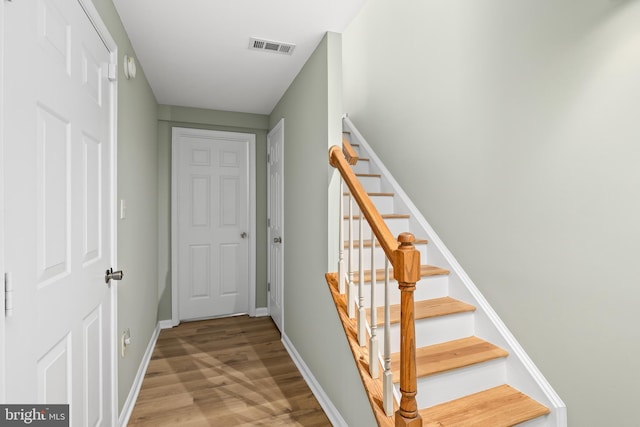 stairway with visible vents, baseboards, and wood finished floors