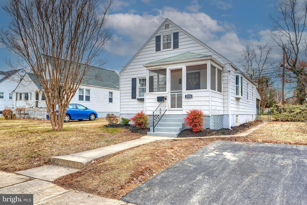 bungalow-style home with a front yard and a sunroom