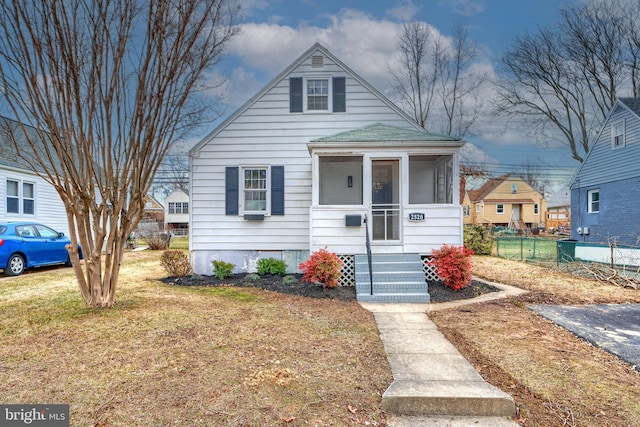 bungalow-style home featuring a sunroom and a front yard