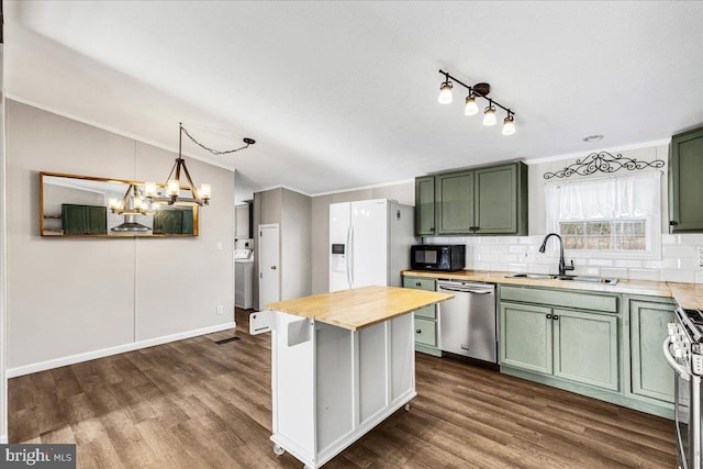 kitchen with appliances with stainless steel finishes, butcher block countertops, a sink, and green cabinetry