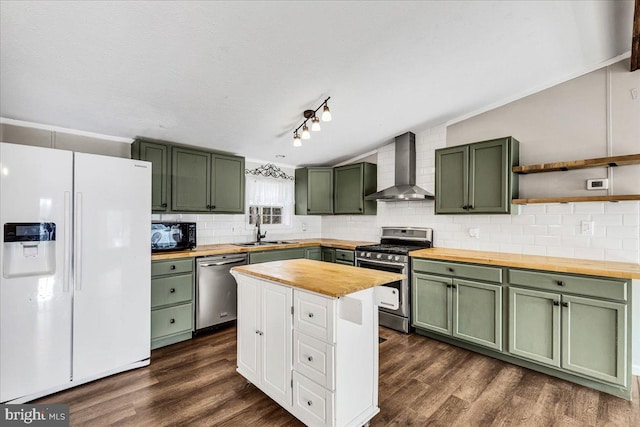 kitchen with green cabinetry, wall chimney exhaust hood, appliances with stainless steel finishes, wooden counters, and a sink