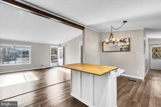 kitchen featuring a textured ceiling, wood counters, visible vents, baseboards, and dark wood-style floors