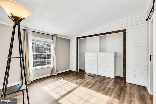 unfurnished bedroom featuring visible vents, lofted ceiling, wood finished floors, a textured ceiling, and a closet