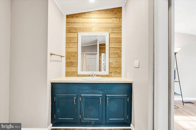 bathroom featuring wood walls, vaulted ceiling, and vanity