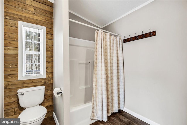 bathroom with ornamental molding, wood walls, toilet, and wood finished floors