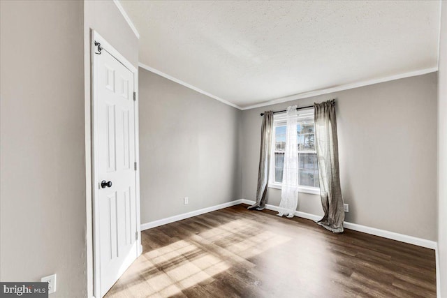 spare room with baseboards, a textured ceiling, ornamental molding, and wood finished floors