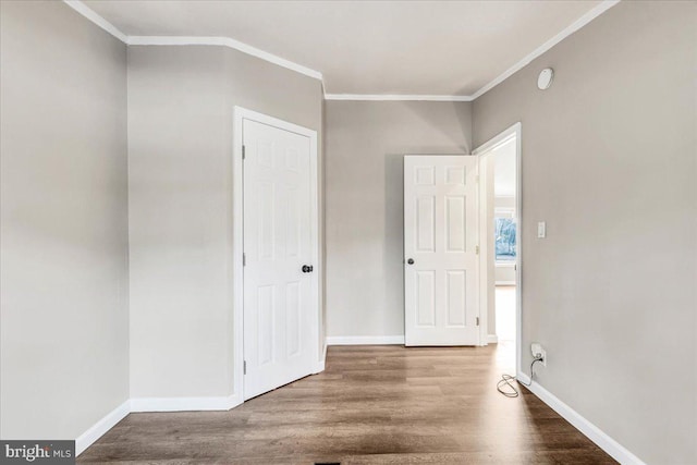 unfurnished bedroom featuring baseboards, wood finished floors, and ornamental molding