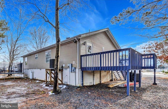 view of home's exterior featuring a trampoline, stairway, and a wooden deck