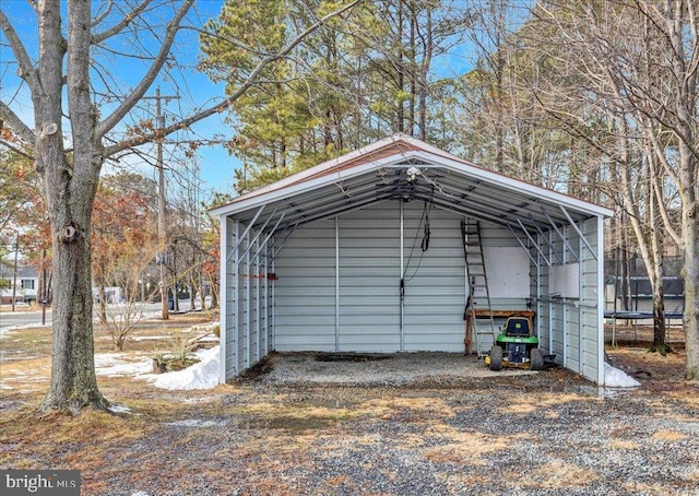 view of outdoor structure with driveway, a trampoline, and a detached carport