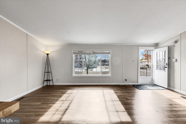 spare room featuring a textured ceiling, wood finished floors, visible vents, and baseboards