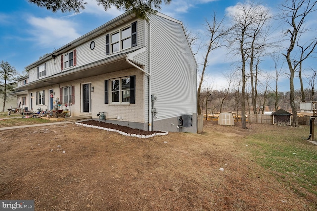 view of front of house with a storage shed, a front lawn, and central air condition unit