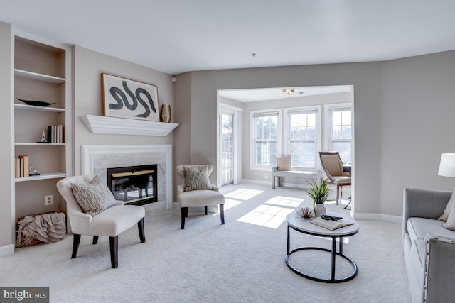 living room featuring light colored carpet, a fireplace, and built in shelves