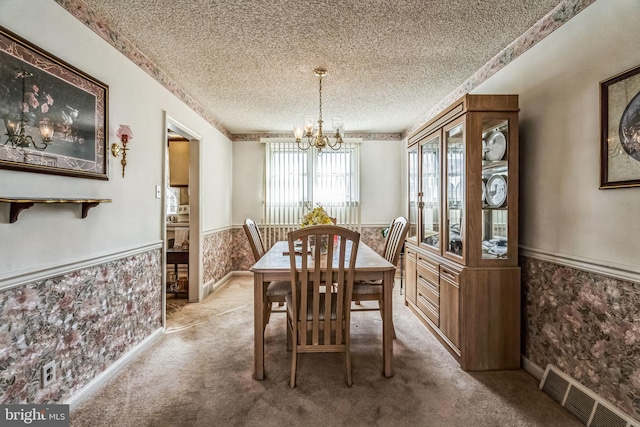 carpeted dining space with a chandelier and a textured ceiling