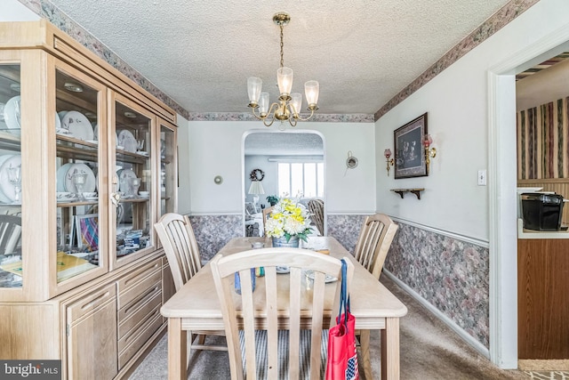 dining room featuring dark carpet, a chandelier, and a textured ceiling