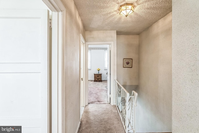 corridor with a textured ceiling and carpet