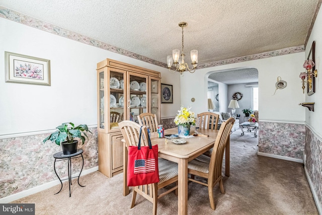 dining area featuring carpet flooring, a textured ceiling, and a notable chandelier