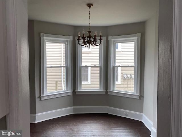 unfurnished dining area with dark hardwood / wood-style flooring and an inviting chandelier