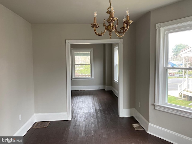 unfurnished dining area with dark wood-type flooring and a chandelier