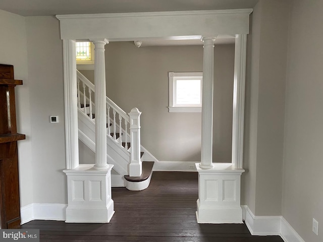 stairway with decorative columns, wood-type flooring, and a wealth of natural light