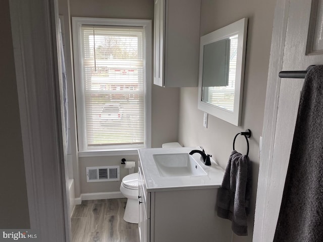 bathroom featuring vanity, wood-type flooring, toilet, and a healthy amount of sunlight