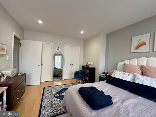 bedroom featuring recessed lighting, multiple closets, and light wood finished floors