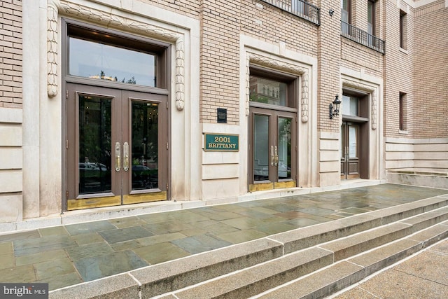 property entrance featuring brick siding and french doors