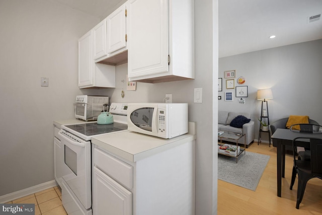 kitchen with visible vents, white cabinetry, white appliances, light countertops, and baseboards