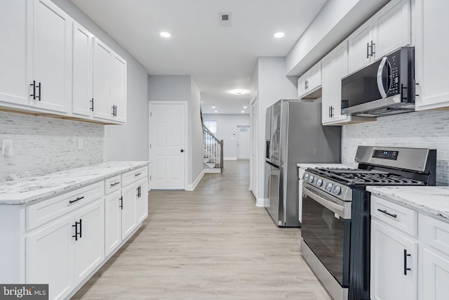 kitchen featuring appliances with stainless steel finishes, white cabinets, and light stone countertops