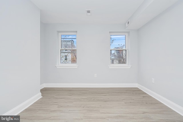 unfurnished room with baseboards, visible vents, plenty of natural light, and light wood-style flooring