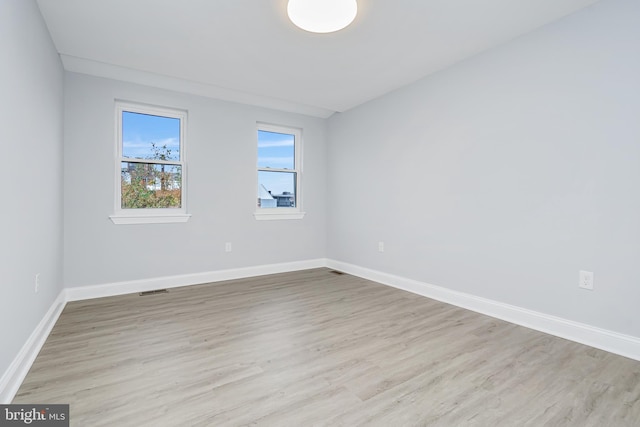 spare room with baseboards, wood finished floors, and visible vents
