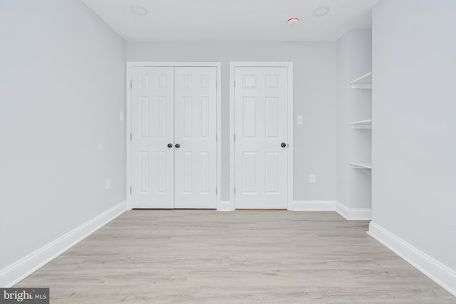 unfurnished bedroom with light wood-style floors, baseboards, and a closet