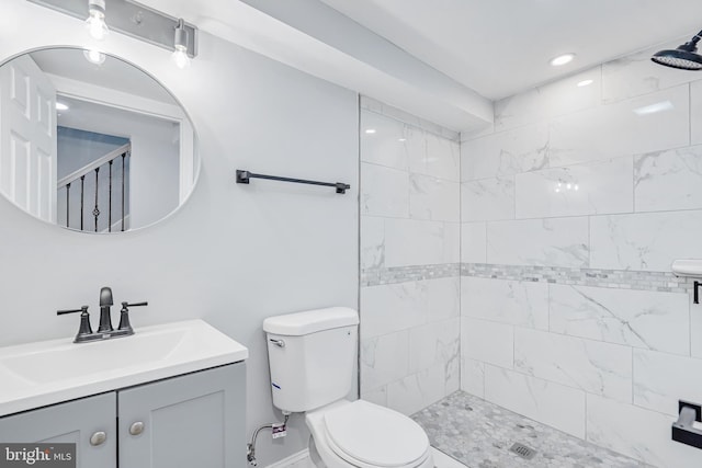 full bathroom with vanity, a tile shower, and toilet