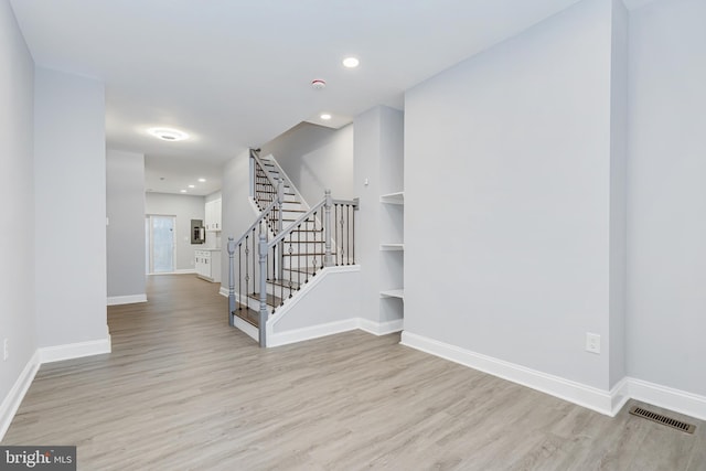 interior space with stairs, baseboards, visible vents, and wood finished floors