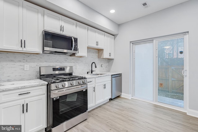 kitchen featuring stainless steel appliances, baseboards, white cabinetry, and a sink