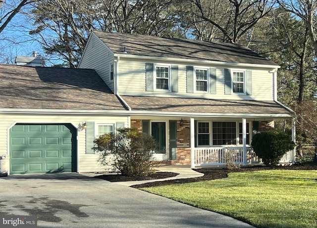 view of front of home featuring a garage, a front lawn, and covered porch