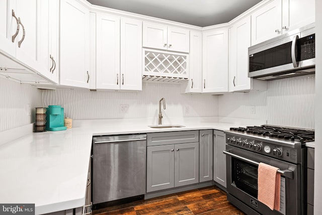 kitchen with appliances with stainless steel finishes, sink, gray cabinetry, and white cabinets