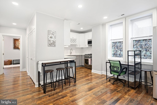 kitchen with dark wood-type flooring, sink, white cabinetry, crown molding, and stainless steel appliances