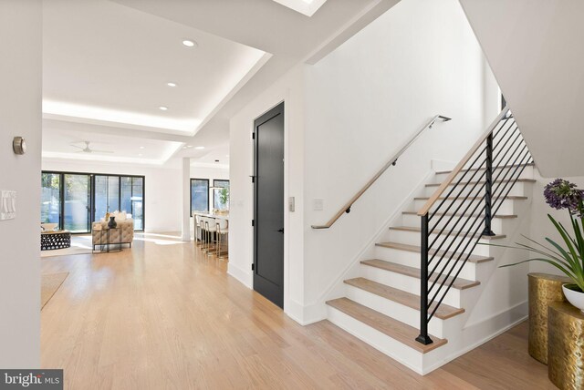 staircase featuring a tray ceiling and hardwood / wood-style floors