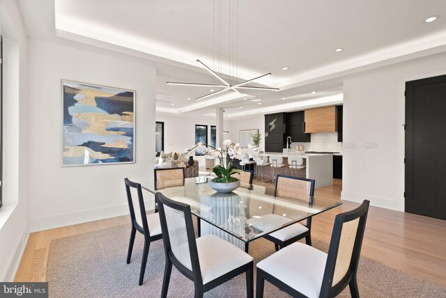 dining space featuring sink, a notable chandelier, and light hardwood / wood-style floors