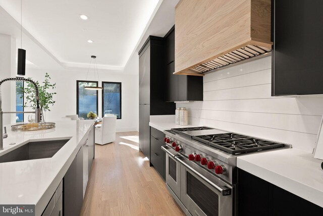 kitchen with sink, premium range hood, double oven range, decorative light fixtures, and a raised ceiling