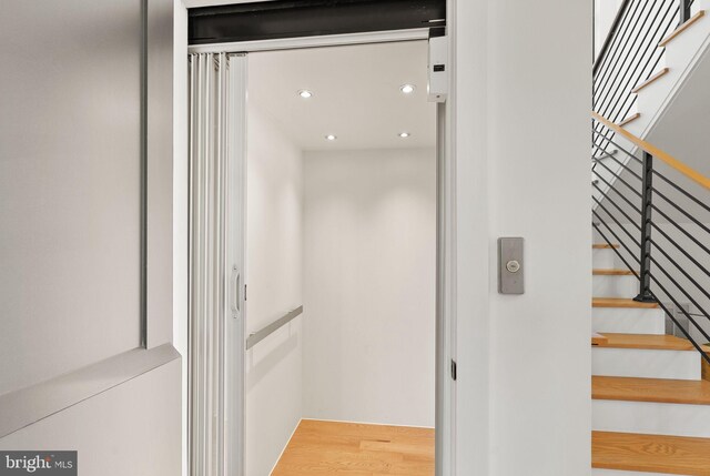 staircase with wood-type flooring and elevator