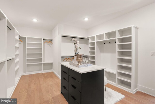 walk in closet with light hardwood / wood-style floors