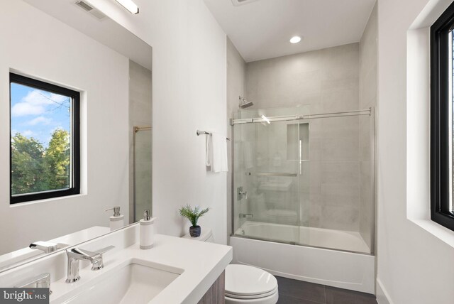 full bathroom with toilet, vanity, shower / bath combination with glass door, and tile patterned flooring