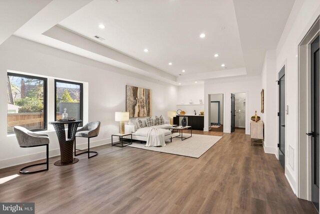 living room with hardwood / wood-style flooring and a tray ceiling