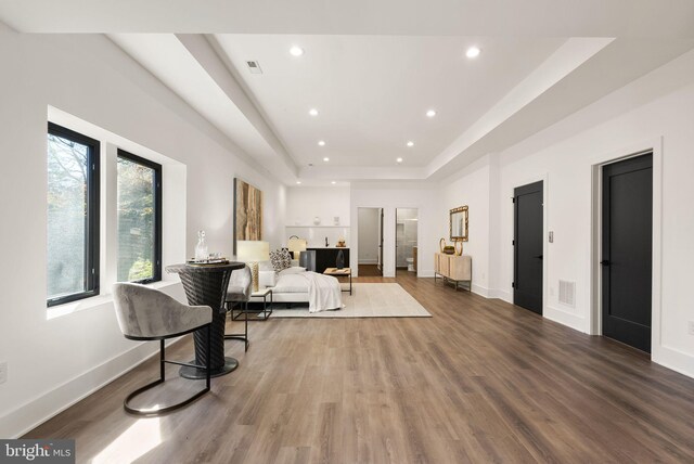 sitting room featuring wood-type flooring and a tray ceiling