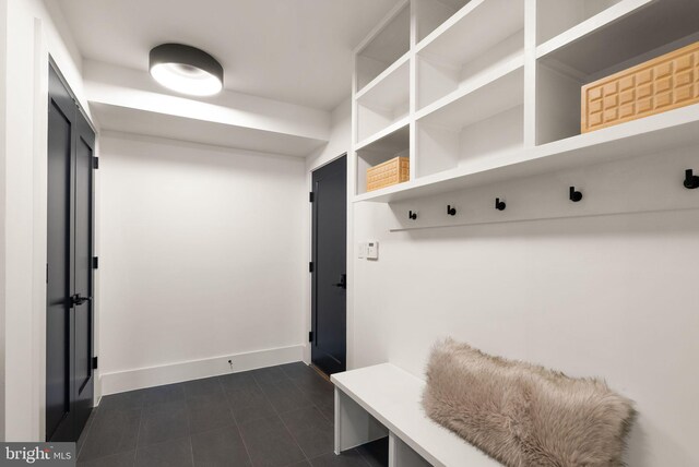 mudroom with dark tile patterned floors