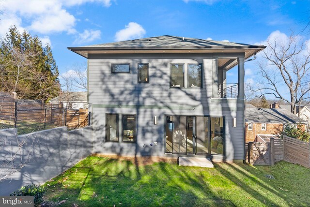 back of property featuring a balcony and a lawn