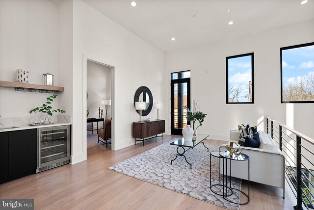 living room with wet bar, beverage cooler, and light wood-type flooring